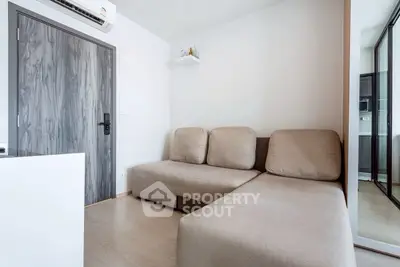 Modern living room with beige sectional sofa and wooden flooring, featuring a sleek air conditioning unit.