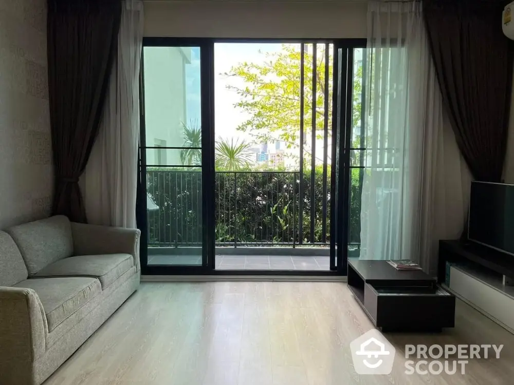 Spacious living room with large sliding glass doors leading to a lush balcony view.