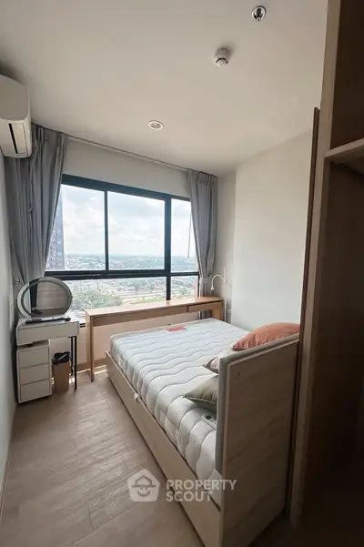 Cozy bedroom with large window offering stunning city views, modern furniture, and ample natural light.