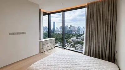 Luxurious bedroom with panoramic city view from floor-to-ceiling windows in modern high-rise apartment.