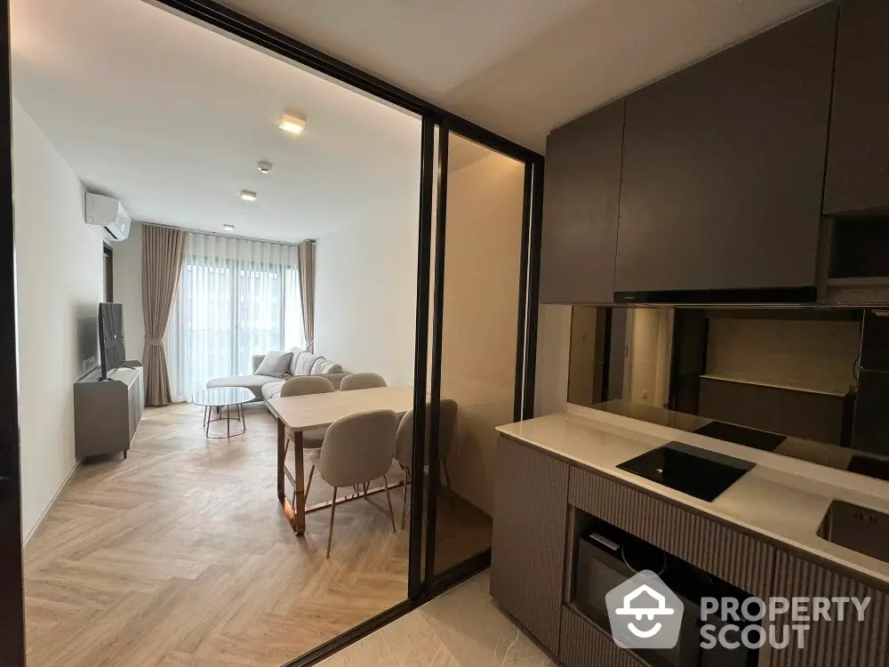 Modern apartment with open layout kitchen and cozy living area, featuring sleek furniture and natural light.