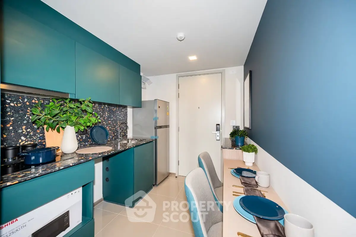 Modern kitchen with teal cabinets and stylish dining area in a compact apartment.
