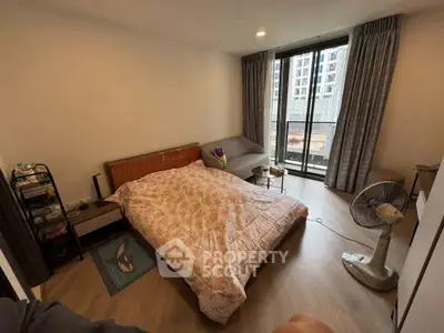 Cozy bedroom with large window and modern furnishings in urban apartment