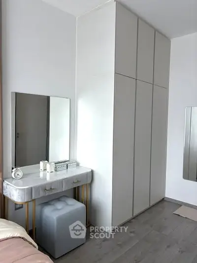 Modern bedroom with sleek wardrobe and stylish vanity in a contemporary apartment.