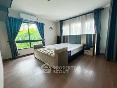 Spacious bedroom with large windows and modern decor in a serene setting.