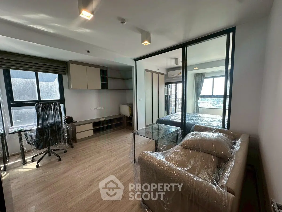Modern apartment interior with glass partition, cozy living area, and natural light.