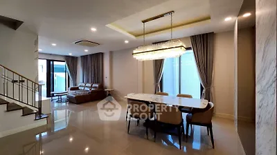 Luxurious open-plan living and dining area with elegant chandelier and modern furnishings.