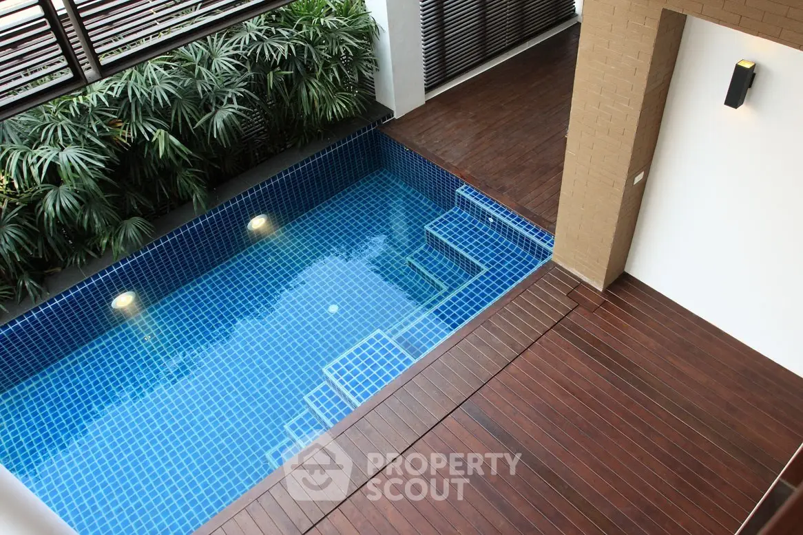 Luxurious indoor pool with elegant wooden deck and lush greenery, perfect for relaxation and leisure.