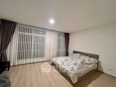 Spacious bedroom with large window and elegant curtains
