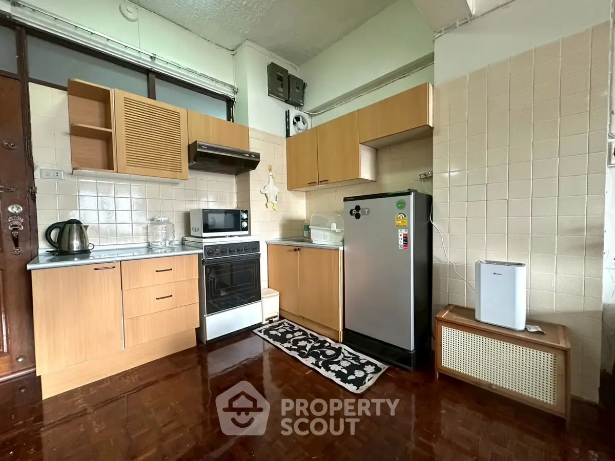 Charming kitchen with wooden cabinetry and modern appliances in cozy apartment.