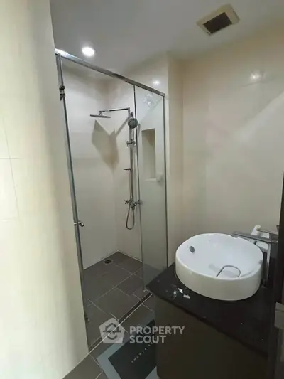 Modern bathroom with glass shower enclosure and sleek basin in a contemporary apartment.