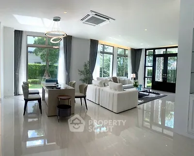 Luxurious open-plan living room with elegant decor and large windows offering garden views.