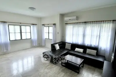 Spacious living room with modern black sofa and large windows for natural light.