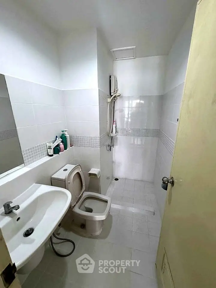 Compact bathroom with shower and modern fixtures in a minimalist design.