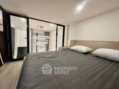 Modern bedroom with stylish lighting and balcony access in a contemporary apartment.