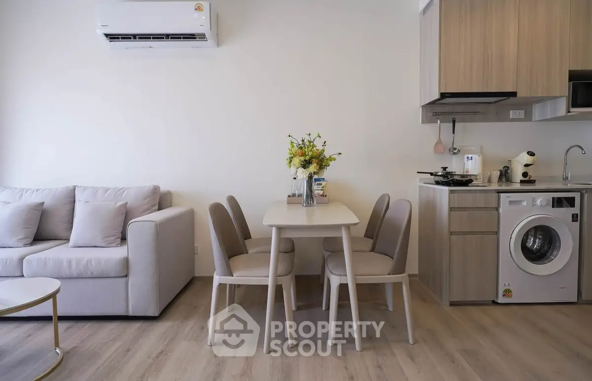 Modern living room with dining area and compact kitchen featuring washing machine and air conditioning.