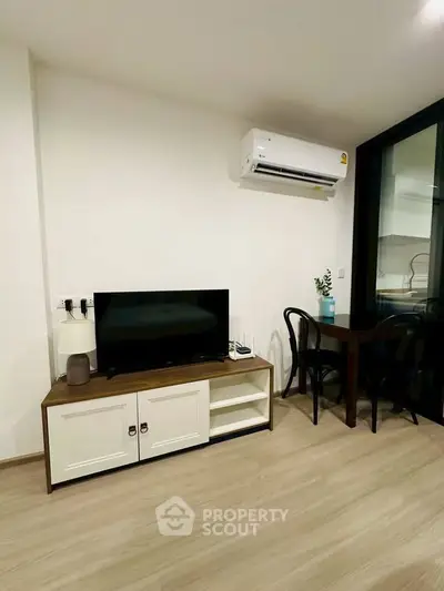 Modern living room with sleek TV stand and dining area, featuring air conditioning and stylish decor.