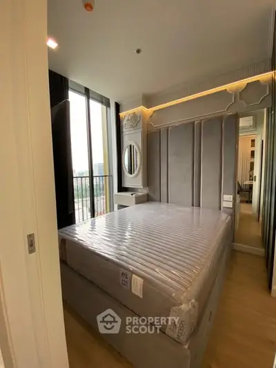 Modern bedroom with stylish decor and large window offering city views.