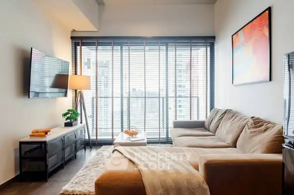 Modern living room with large sofa, wall-mounted TV, and city view through large windows.