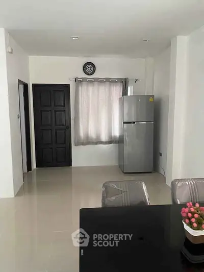 Modern kitchen with sleek fridge and dining area, bright and inviting space.