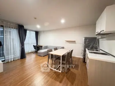 Spacious modern living room with open kitchen and dining area, featuring sleek furniture and natural light.