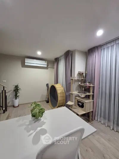 Modern living room with stylish decor and natural light, featuring a unique cat tree and air conditioning.