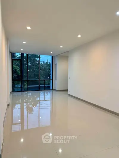 Spacious modern living room with large windows and glossy tiled floors.