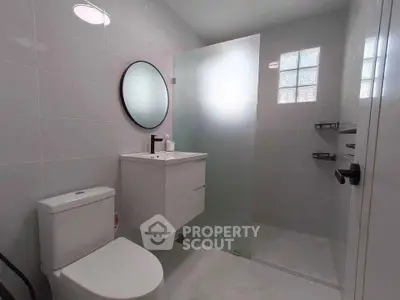 Modern bathroom with sleek fixtures and frosted glass shower in a contemporary home.