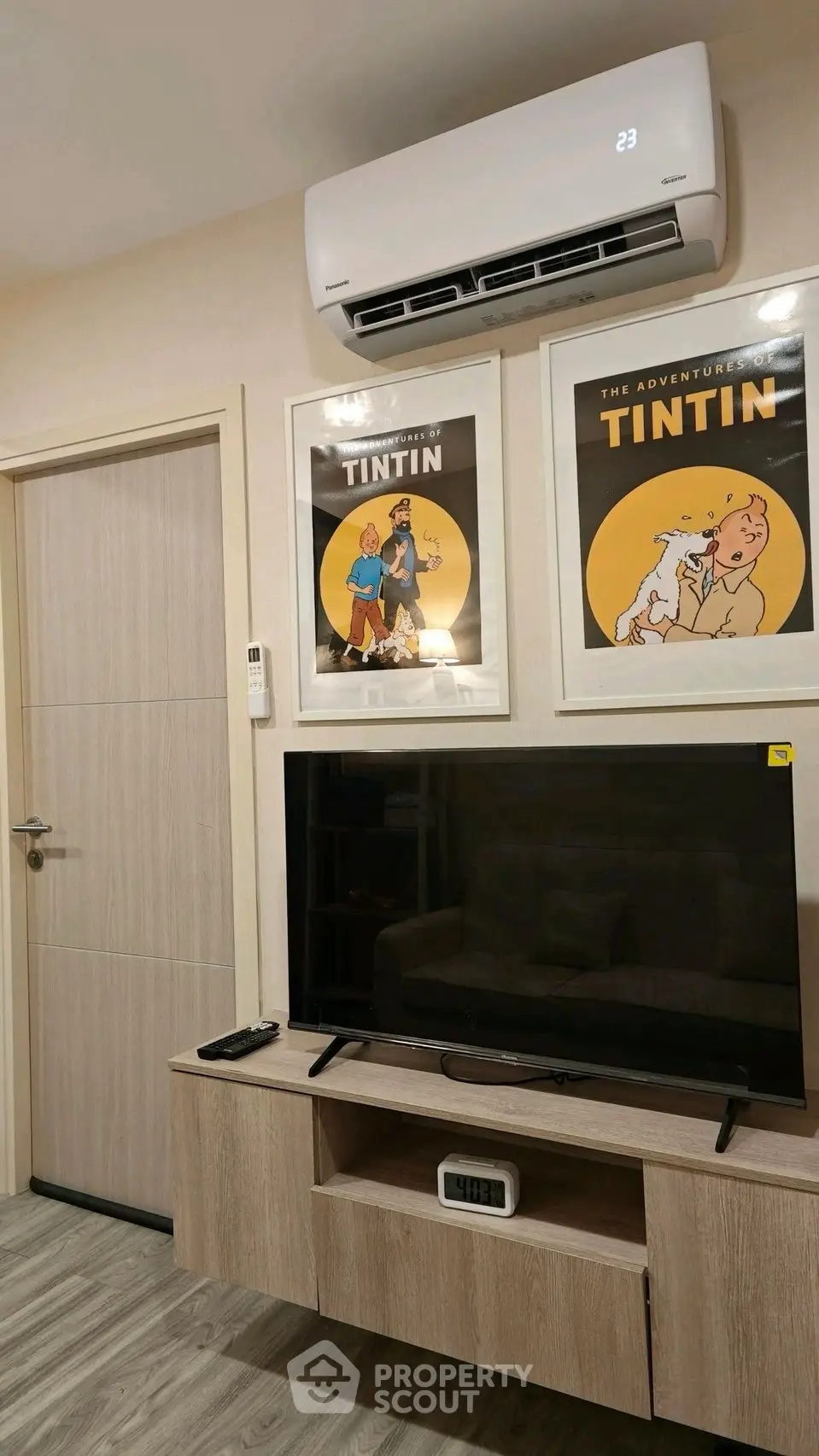 Modern living room with air conditioning and stylish Tintin artwork above TV unit.