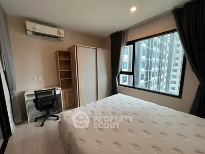 Modern bedroom with large window and city view, featuring a comfortable bed and workspace.