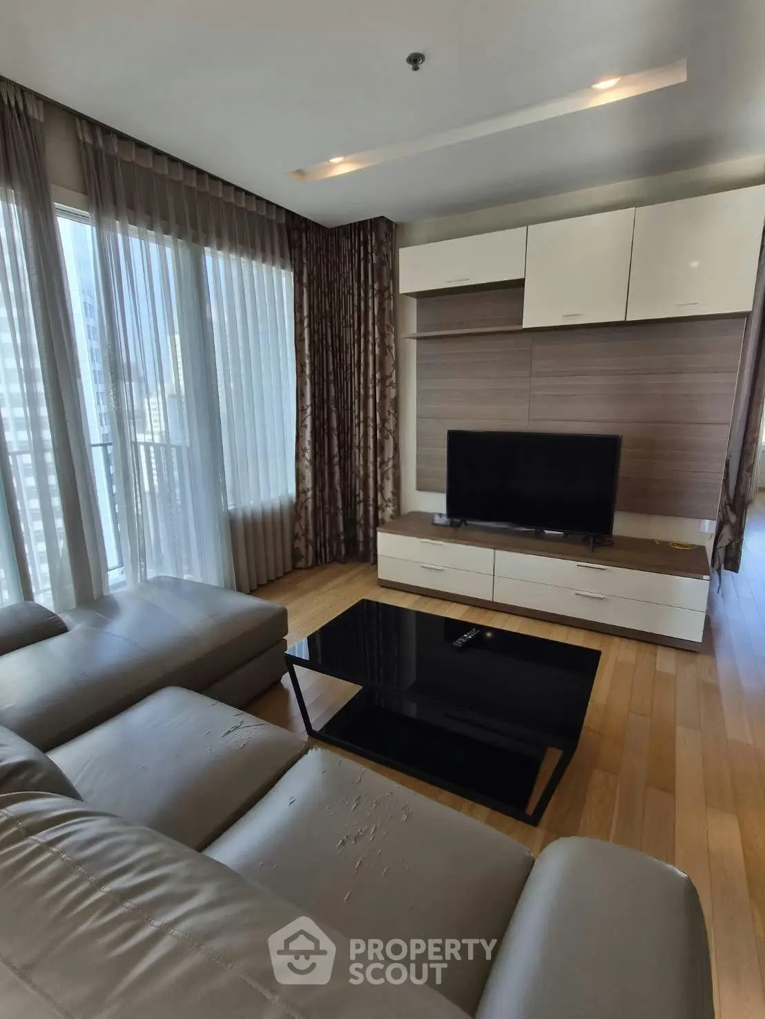 Modern living room with sleek furniture and large windows offering natural light.