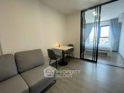 Modern studio apartment with cozy living area and bedroom separated by glass partition.