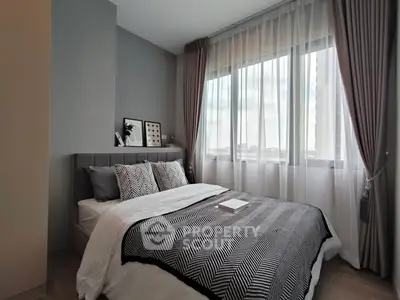 Modern bedroom with stylish decor and large window for natural light.