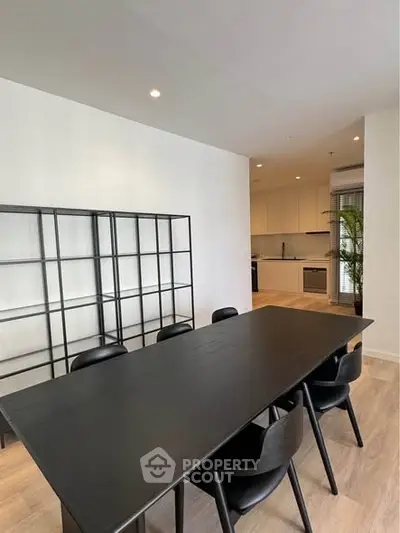 Modern dining area with sleek black table and chairs, open kitchen layout, and stylish shelving.