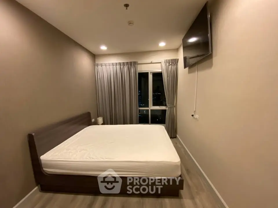 Spacious bedroom with modern decor and large window offering city views.