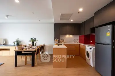 Modern open-plan kitchen with dining area, featuring sleek appliances and stylish decor.