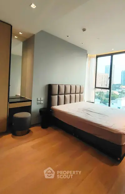Spacious bedroom with city view and modern furnishings in a high-rise apartment.