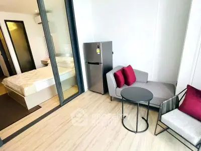 Modern studio apartment with cozy living area and bedroom, featuring sleek furniture and wooden flooring.