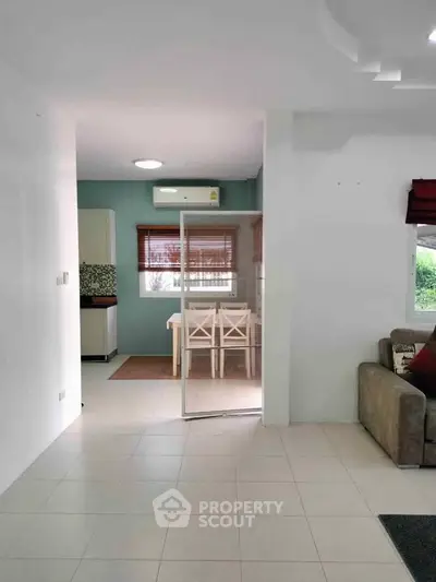 Spacious open-plan living area with modern kitchen and dining space, featuring natural light and stylish decor.