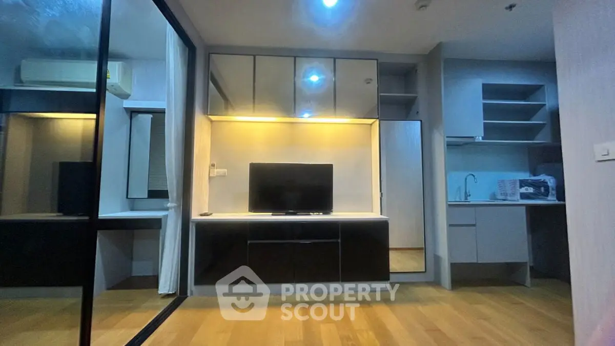Modern living room with sleek cabinetry and built-in TV unit, featuring ambient lighting and mirrored accents.