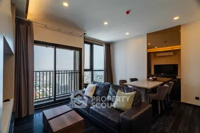 Modern living room with city view, stylish furniture, and open layout in high-rise apartment.