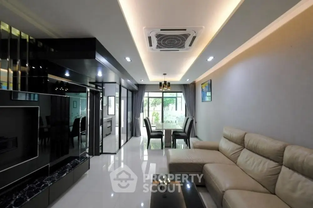 Modern living room with sleek design and spacious dining area, featuring elegant lighting and contemporary furniture.