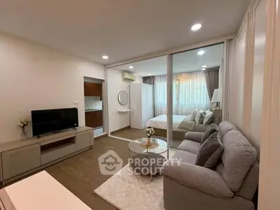 Modern open-plan living room with cozy sofa and bedroom view