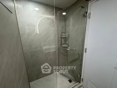 Modern bathroom with glass shower enclosure and sleek tile design.