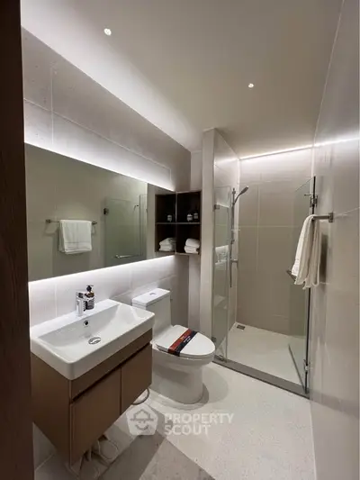 Modern bathroom with sleek fixtures and glass shower enclosure in a contemporary apartment.
