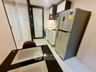 Modern kitchen with sleek appliances and dining area in compact layout.