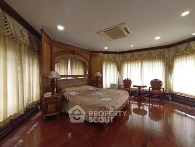 Luxurious bedroom with elegant drapery and polished wooden floors, featuring classic furniture and ambient lighting.