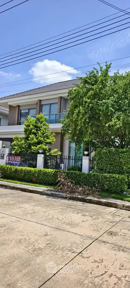 Stunning modern house with lush greenery and spacious balcony in a serene neighborhood.