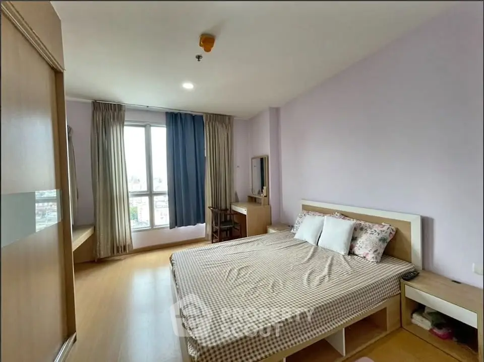 Spacious bedroom with large window and modern furnishings in a high-rise apartment.