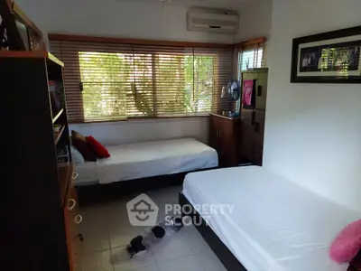 Cozy bedroom with twin beds and large windows offering natural light and garden views.